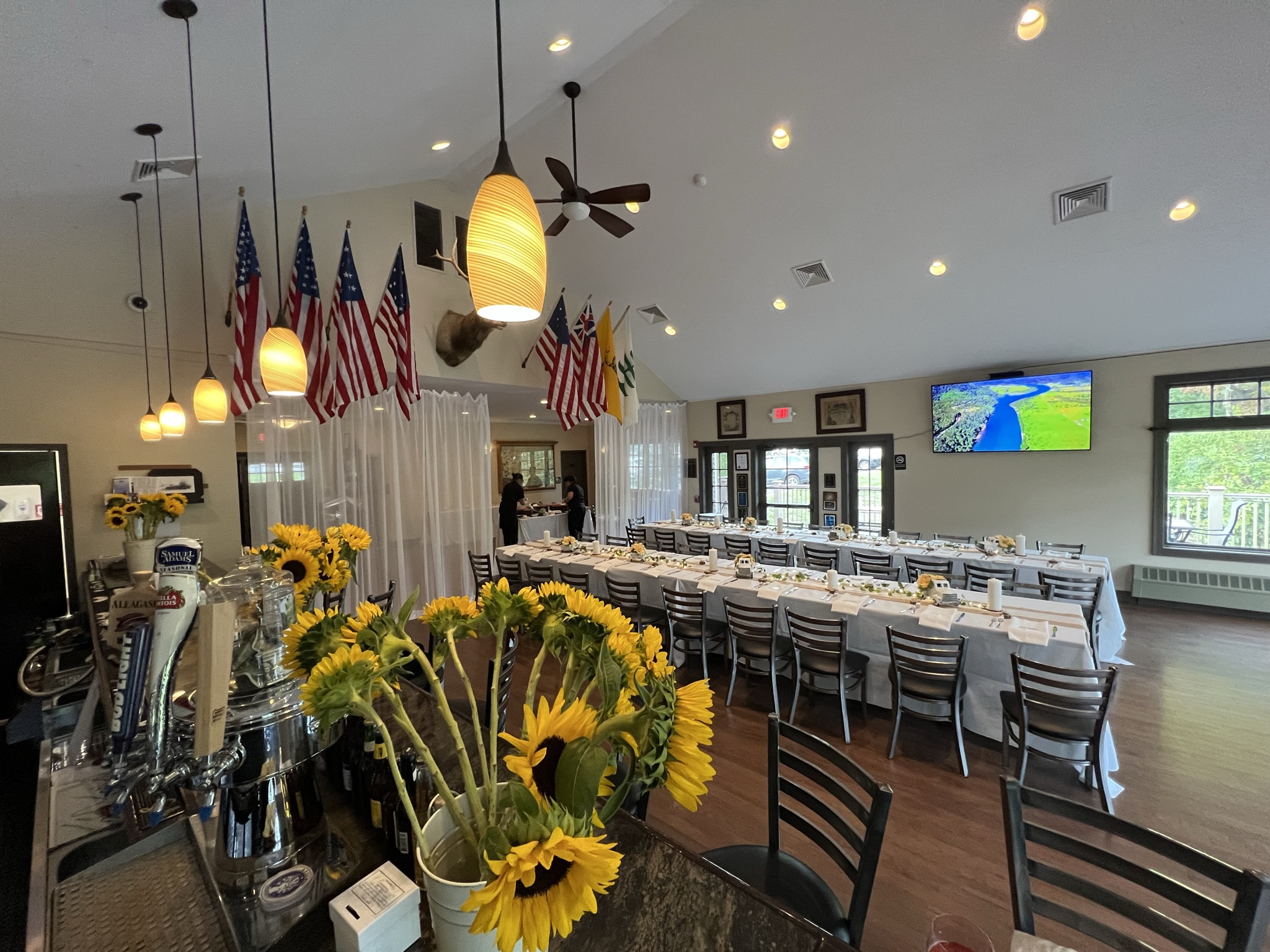 Event room set up with long banquet tables, flags, and a bar area